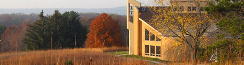 Holy Wisdom Monastery building overlooking woods and lake in distance