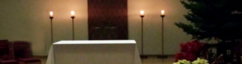 candle light and plain, bare Christmas tree await Christmas Eve services in the assembly room