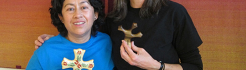 Sojourners Paz and Denise standing together holding their favorite crosses