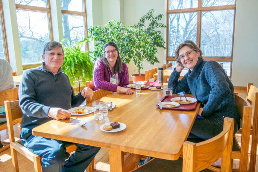 Three people looking at the camera and having a meal at the monastery